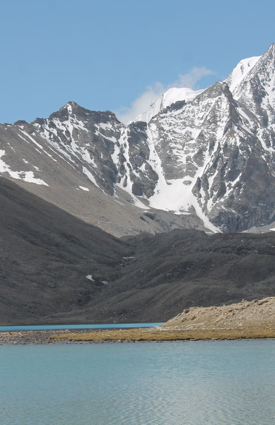 Image of a mountain range partially covered with snow and water body in the front