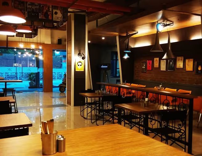 View of Mumbai Masala Restaurant with contemporary seating, warm decor, and large window - Max Hotel Prayagraj.