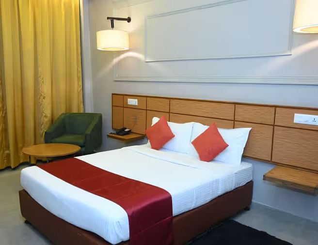 A well-designed hotel room with two beds, modern lighting, and a cosy seating area - Max Hotel Prayagraj.