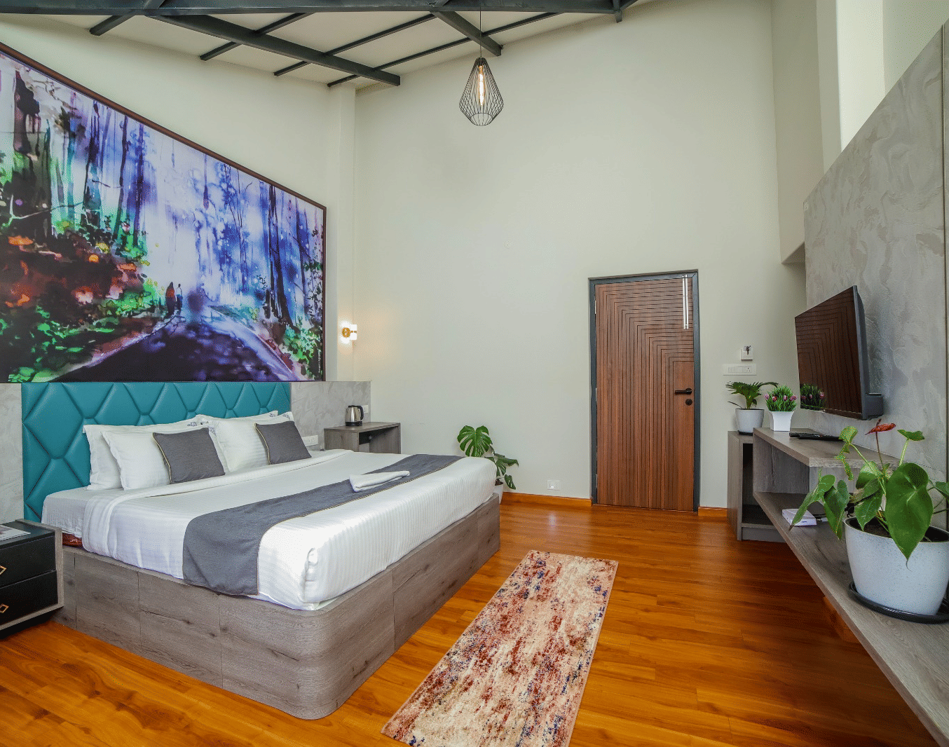 Spacious room at MYST Resorts, Doddabetta, Ooty with a queen size bed, wooden flooring, wall art, and a TV shelf with plants.