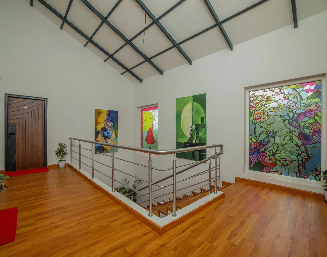 Common walkway on the upper floor of MYST Resorts, Doddabetta, Ooty, featuring potted plants, a railed staircase leading down, and a doorway to an upper-floor bedroom.