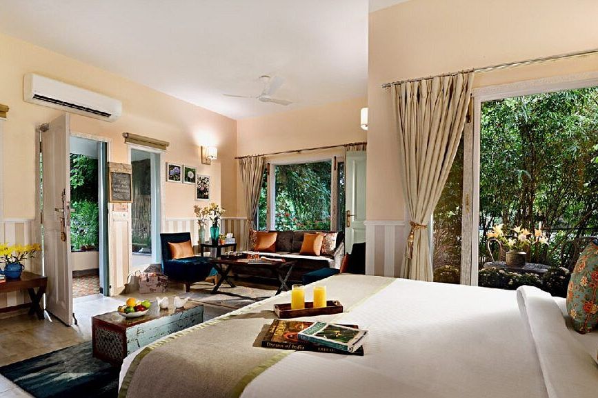 Spacious bedroom with a large bed, seating area, glass doors, and greenery visible outside at Karma Chalets.