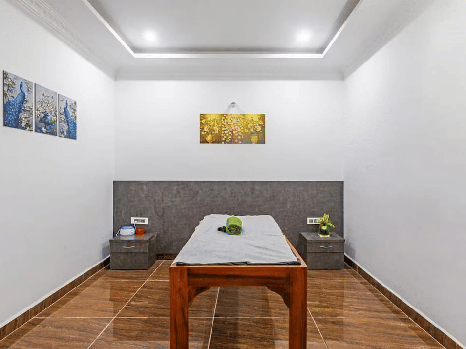 Minimalist spa room with a wooden table and decorative wall art at Siri Ambari Resorts and Spa.