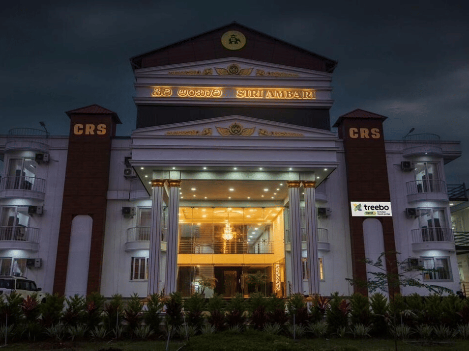 Night view of the grand exterior of Siri Ambari Resorts and Spa, featuring a majestic white building with landscaped gardens in front.