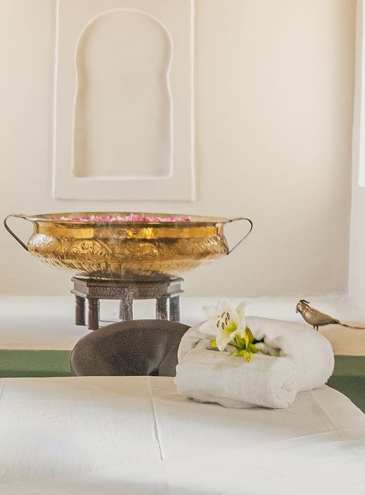 A serene spa treatment room with soft lighting, featuring a massage table, arched alcove, and calming green accents.