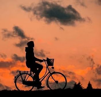 Silhouette of a person riding a bike with a beautiful sunset in the background.