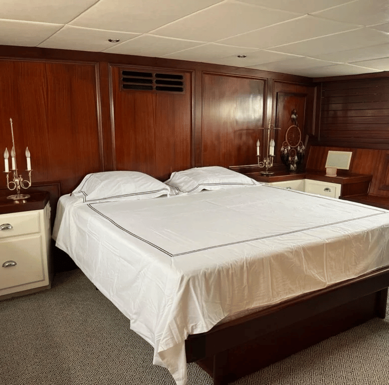 A double bed with dark wooden interiors inside the cabin of the Dreamcatcher featuring a double bed in the middle.