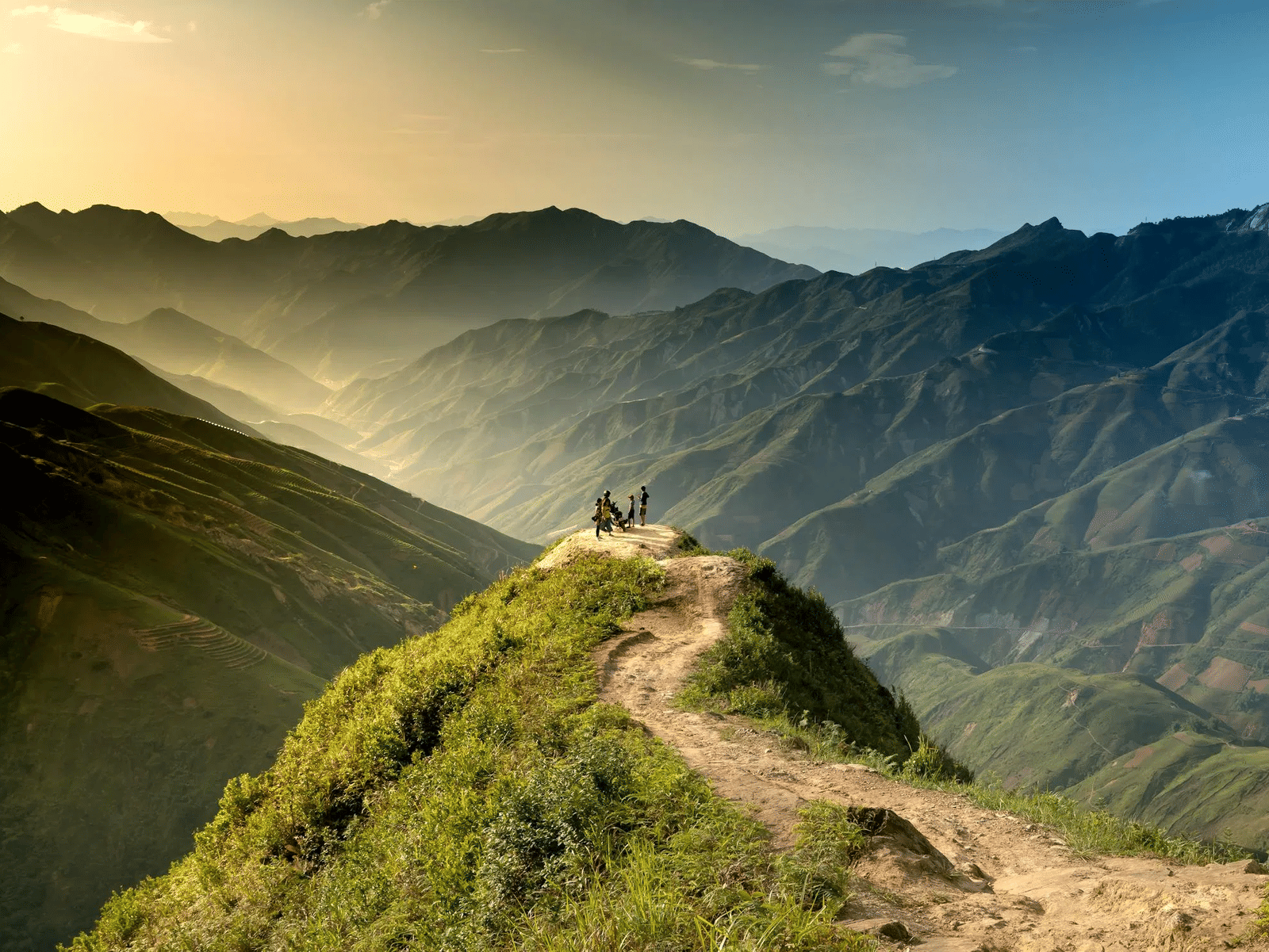 Winding dirt path along a ridge with misty hills in the background.