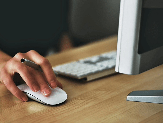 Image of a desktop, keyboard and person using a mouse