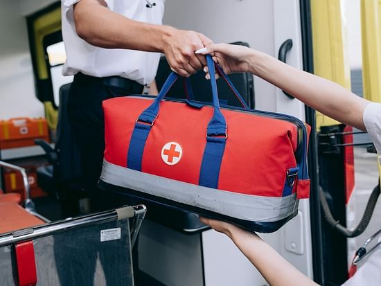 A person handing a first aid kit bag to another person