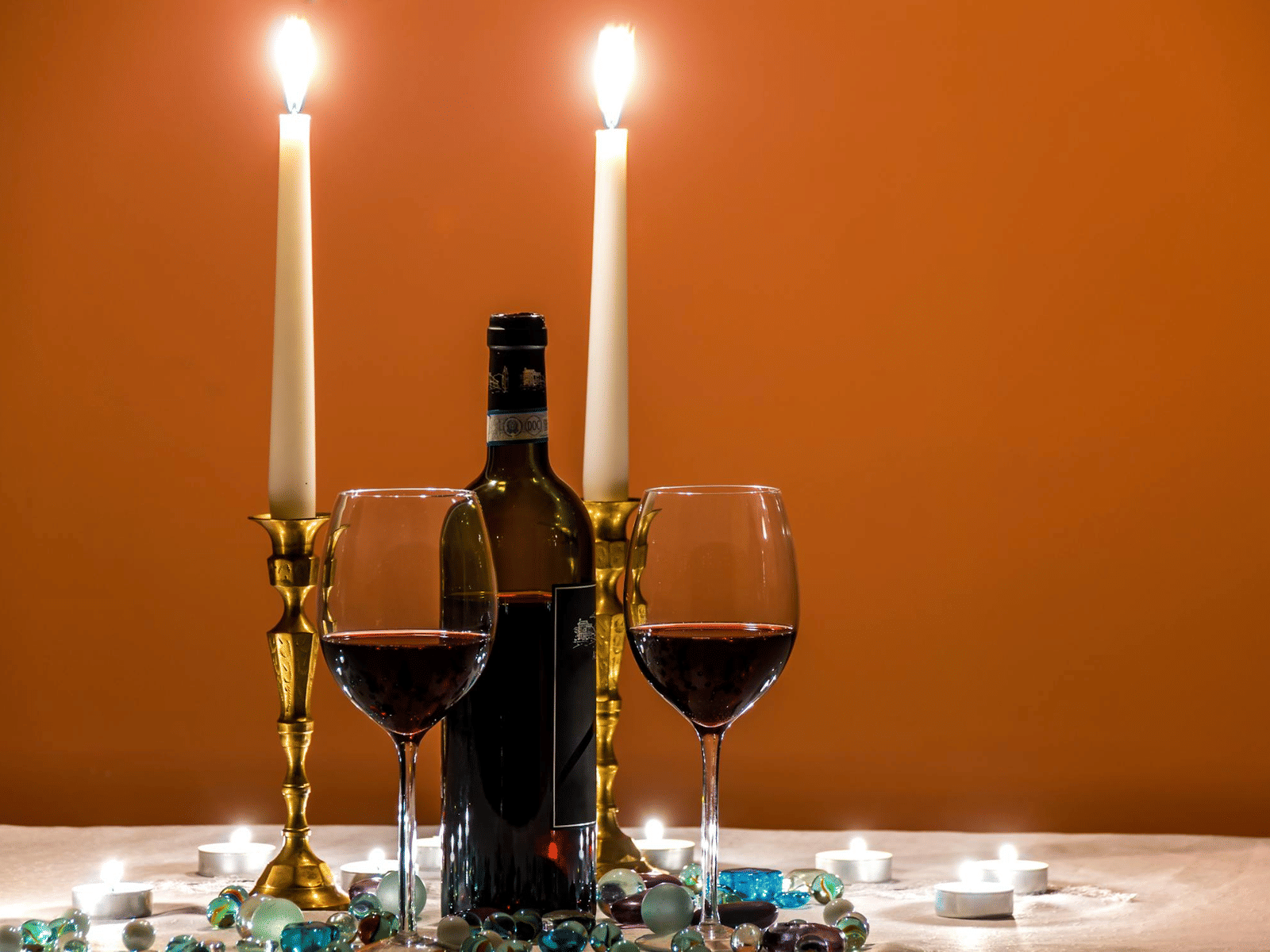 A table set with two glasses and two lit candles.