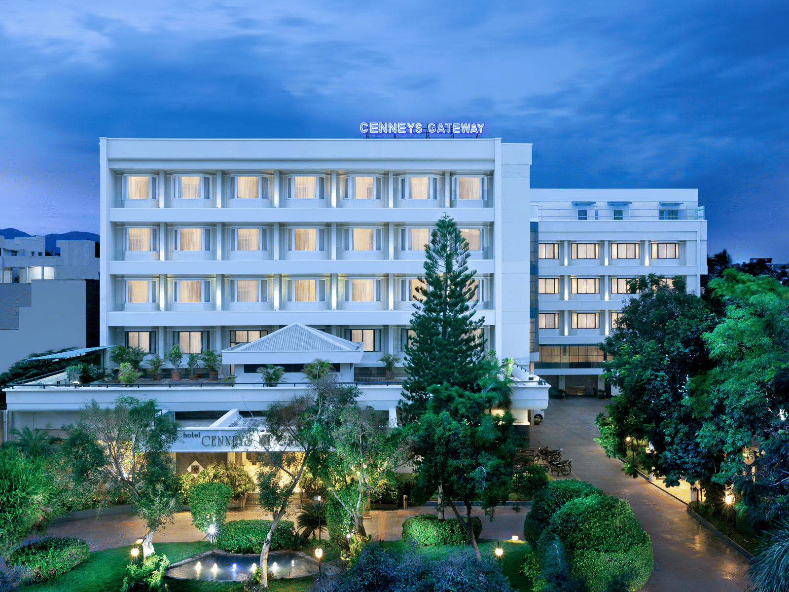 A facade view of Cenneys Gateway against the sky, surrounded by trees and plants in the front.