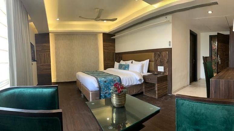 A bedroom with a neatly made bed, teal chairs, and a curved ceiling, showcasing a modern interior - VITS Gurugram