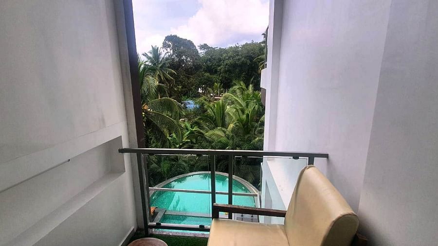 A view from a hotel balcony with a railing, looking down onto a swimming pool surrounded by lush green trees - Sea Hills Hotels, Sri Vijaya Puram (Port Blair)