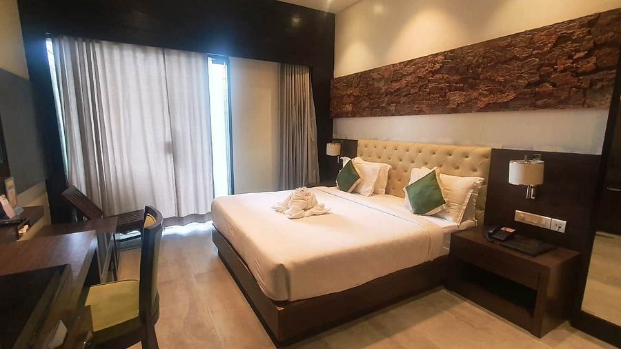 A hotel bedroom with a large bed, a desk area, and a television, showcasing a blend of dark wood and lighter wall finishes - Sea Hills Hotels, Sri Vijaya Puram (Port Blair)