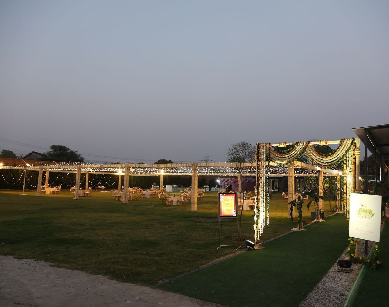 Lawn area at Tisya Farms, Gurgaon with decorative entrance and tented structures captured during daylight.