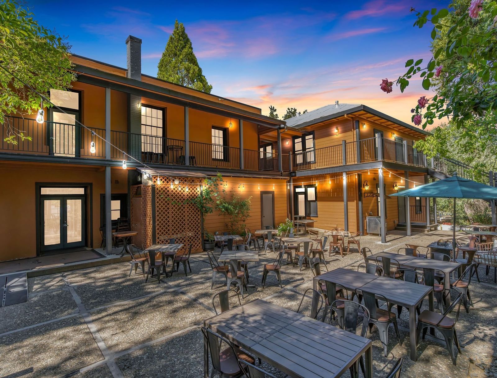 A view of the exterior of The Groveland Hotel with tables and chairs arranged in the backyard