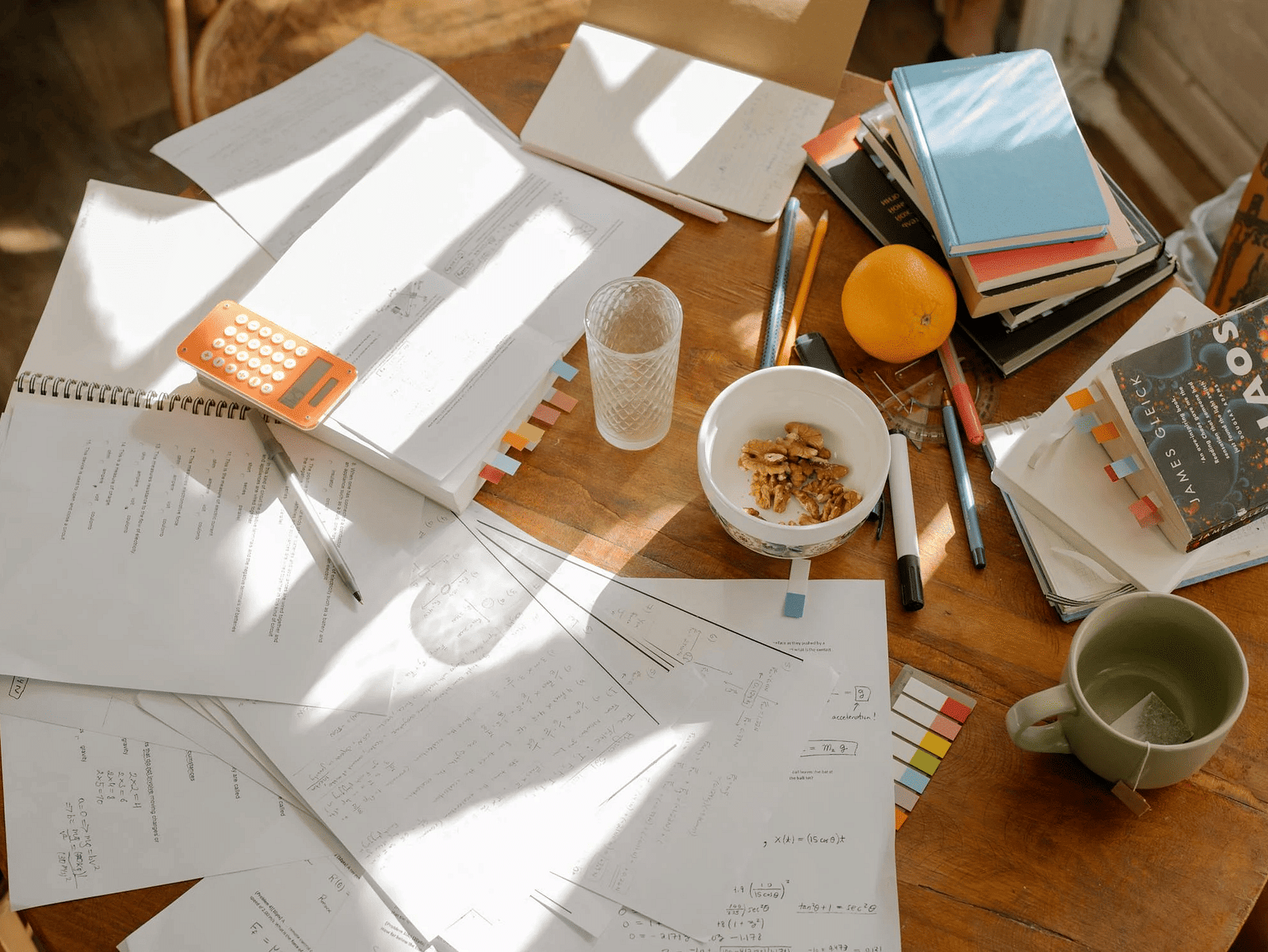 A image of messy desk with papers, books, and a cup of coffee.