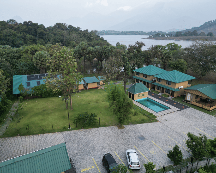 Wide aerial shot showing the resort layout including the swimming pool, guest cottages, and surrounding forest - Ibex Resorts, Malampuzha (Kava Eco Camp and Caravan Park)