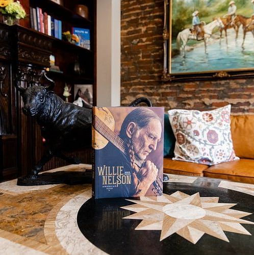 A  inviting interior with a fireplace, stylish decor, and a book featuring a musician on the table. - The Grand Hotel & Ballroom, McKinney