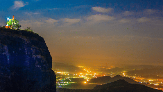 a panoramic view from a hill under vibrant sky showcasing the lit city