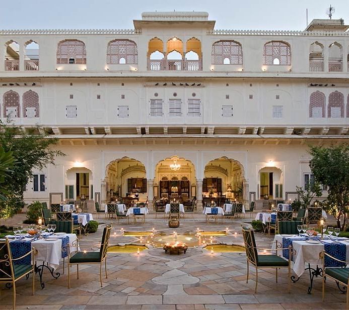 A verandah with comfrtable chairs and tables at Samode Haveli