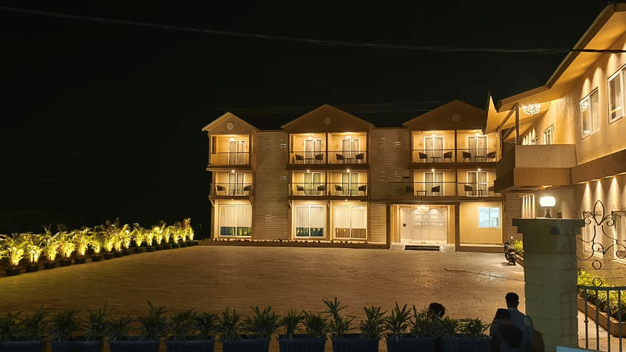 A facade view of illuminated multi-storey buildings and a paved courtyard at night at Savyasaachii Hotel.