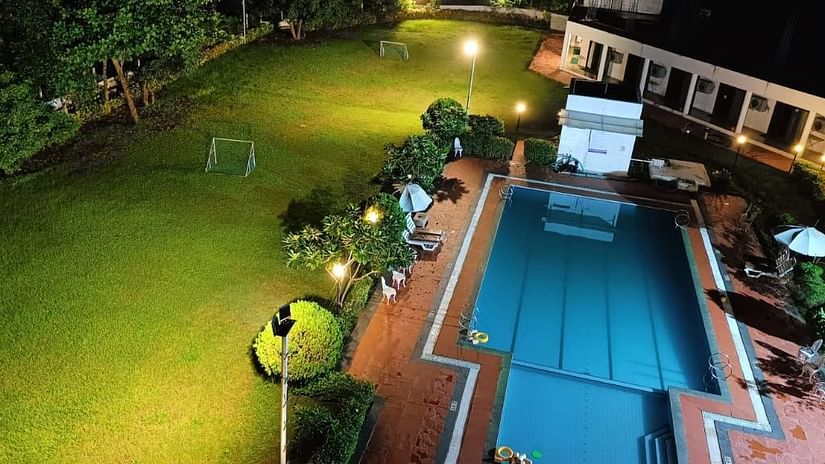 an aerial view of the lawn area next to the swimming pool in the night - VITS Kamats Resort, Silvassa