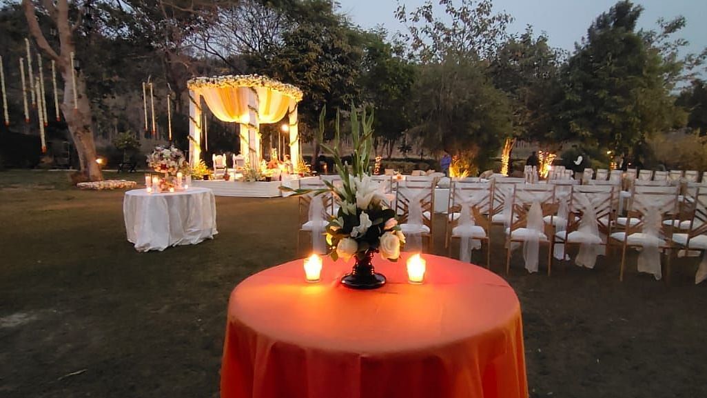 An image of outdoor banquet hall with decorated seats and a table placed at the centre