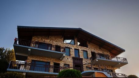 The homestay illuminated under the twilight sky, with intricate architectural detailing and inviting balconies. - Blusalzz Homes The Himalayan Bungalow, Almora