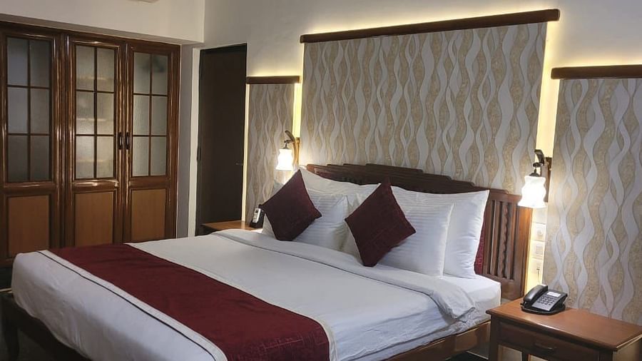  1Damanganga Valley Resorts Pvt Ltd - the king size bed with maroon pillows and a duvet offered at the Director's Suite in Daman