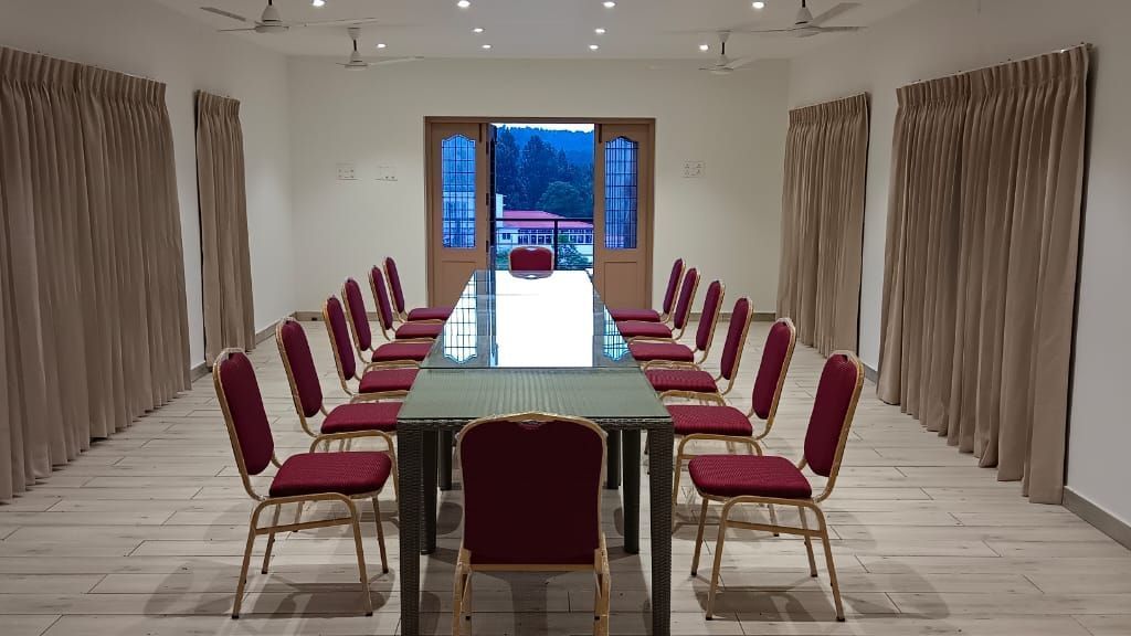 Front-view shot of the Green Park hall with chairs and tables arranged in boardroom setting at WOW Naturefull Resorts.
