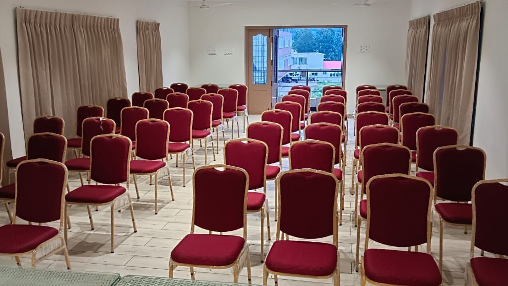 The Green Park hall featuring a lot of cushioned chairs well-arranged in rows facing opposite to the entrance door at WOW Naturefull Resorts.