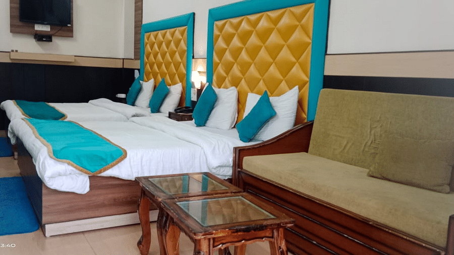 Four Bed Deluxe room with a sofa on the side at Hotel Panchvati Inn, Joshimath