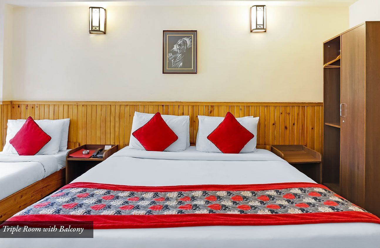 A front view of the beds placed in a room that has a glass window | Summit Newa Regency & Spa, Pelling