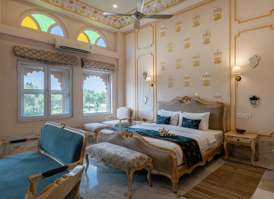 The elegant Maharaja Suite at Umaid Palace, luxury rooms near Delhi, featuring a king-size bed, futons, sofa, lamps, and side tables, and offering traditional decor.