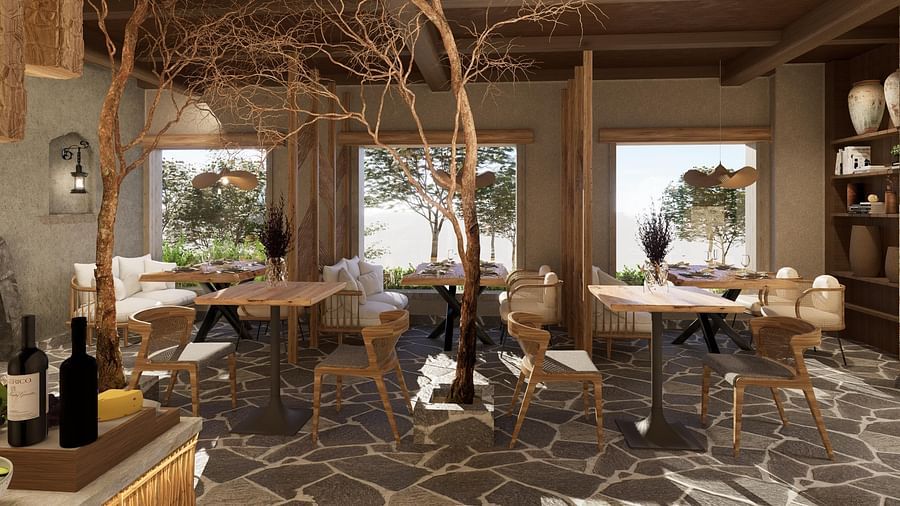 Side view of the restaurant at The Evren, Vagator, with arranged tables, chairs, and windows overlooking greenery.