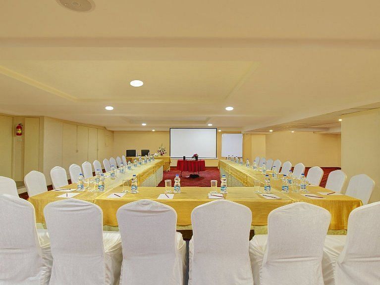 Chairs arranged around a big U shaped table for conference purposes, with limited decorations and a white screen at the front for the presenter - Monarch Hotels