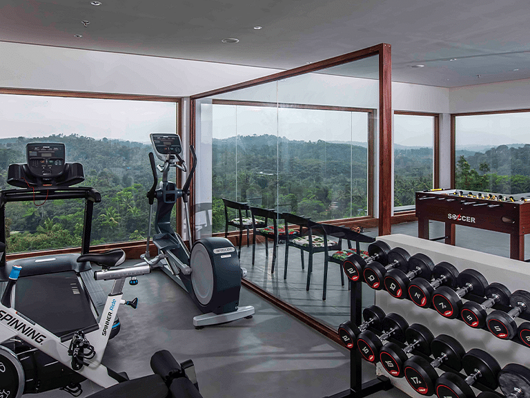 Modern gym with large windows providing views of greenery and hills.