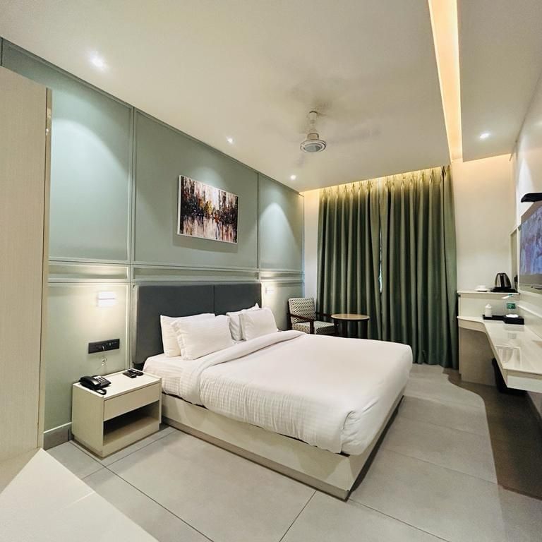 A superior room with a well-prepared bed, an adorned wall, a TV, a tea & coffee maker and a comfortable sofa chair - Five Elements Hotels Goldleaf, Haldwani