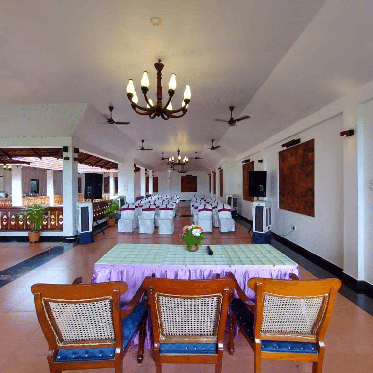 Spacious banquet hall setup with head table seating and chandeliers at The Travancore Heritage Beach Resort, a beach resort near Kovalam