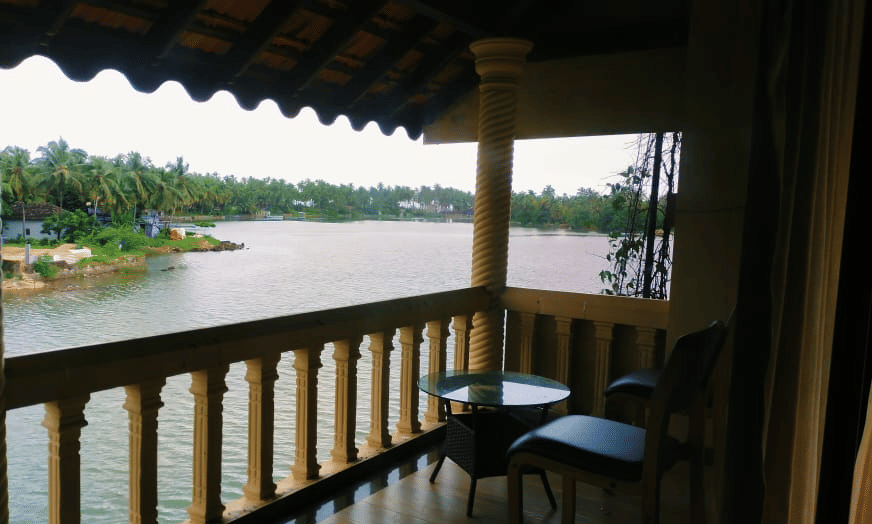 Balcony overlooking the water with chairs and table  with fence at Paradise Lagoon Resort, Udupi.
