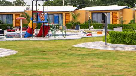 An outdoor garden area with lawns, play structures, and charming cottage-style buildings.