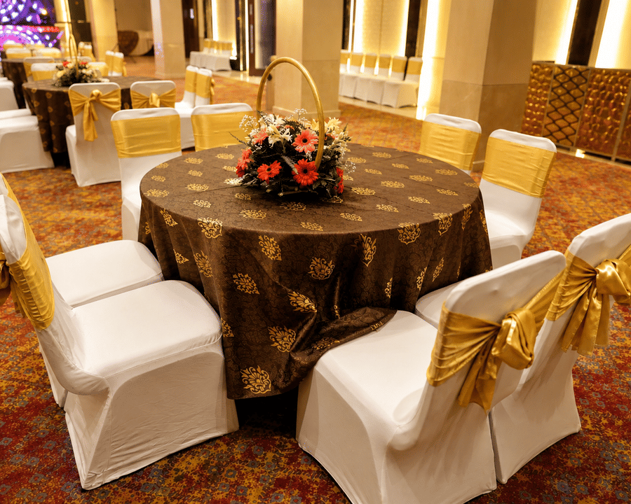 Round banquet table setup with a floral centrepiece and covered seating arrangement at Ambrosia Sarovar Portico, Haridwar.