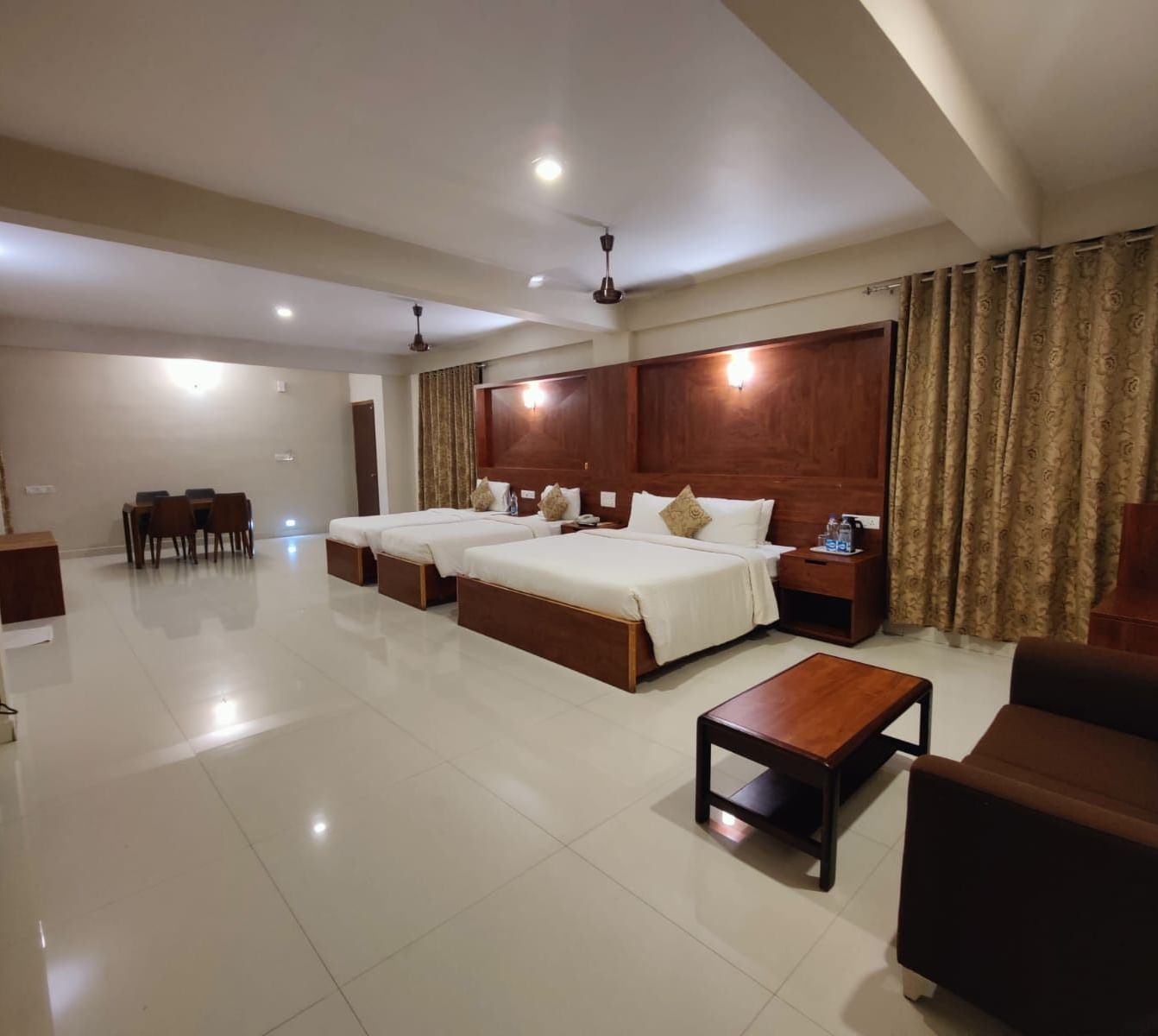 Spacious Deluxe Family Room at Woodstock Resorts, Coorg with twin beds, wooden furniture, and bright, airy interiors.