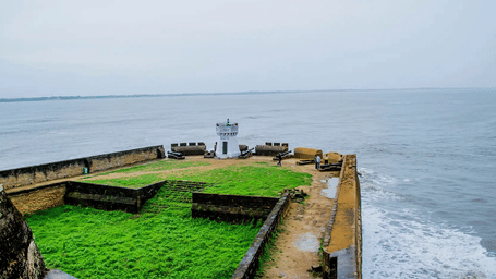 A concrete wall with benches overlooking a turbulent sea.