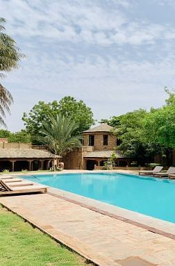 An image of a swimming pool with lounges near it and greenery around - MANVAR Resort & Desert Camp