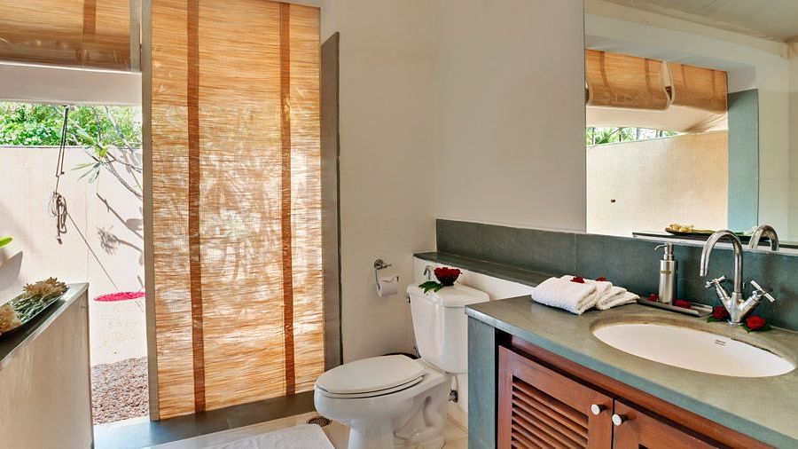 A bathroom with a sink and mirror, sliding glass doors leading to a patio, natural light - Shreyas Retreat