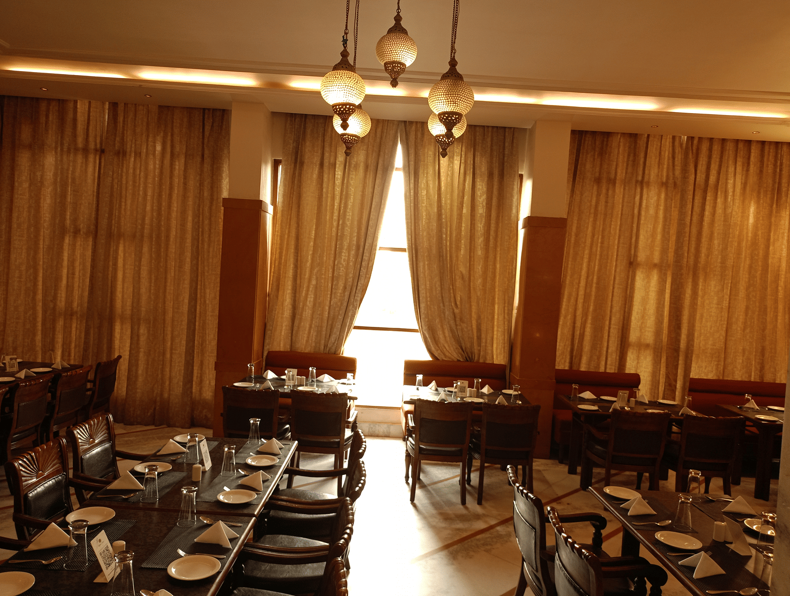 Restaurant at Hotel Gold, Panipat with arranged dining tables, chairs, and hanging lights.