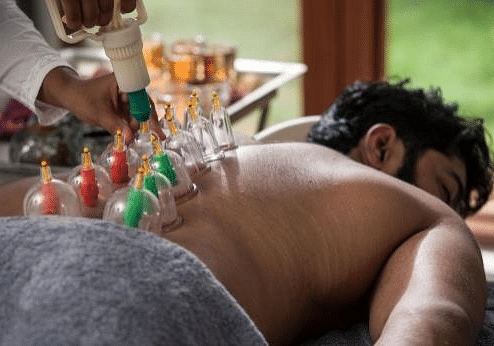 Man receiving cupping therapy on back, colorful cups, blurred background, close-up shot of treatment- Shreyas Retreat
